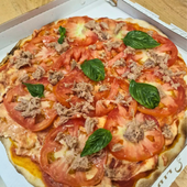 Pizza al pomodoro e basilico con tonno su un coperchio di cartone