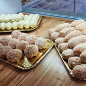 Vassoi di pasticcini ricoperti di zucchero su piatti dorati in una vetrina di una pasticceria.