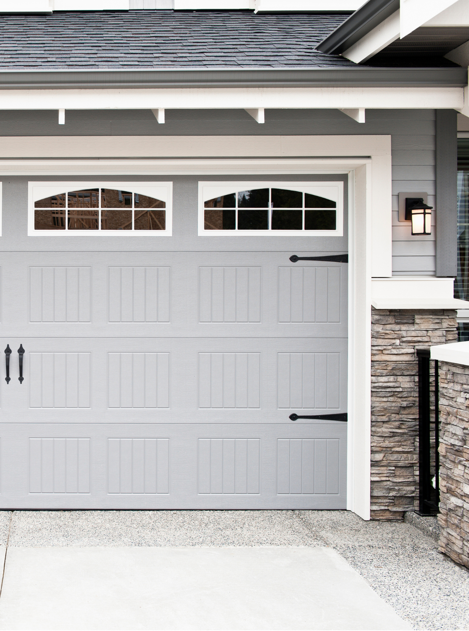 A gray garage door is sitting in front of a house.