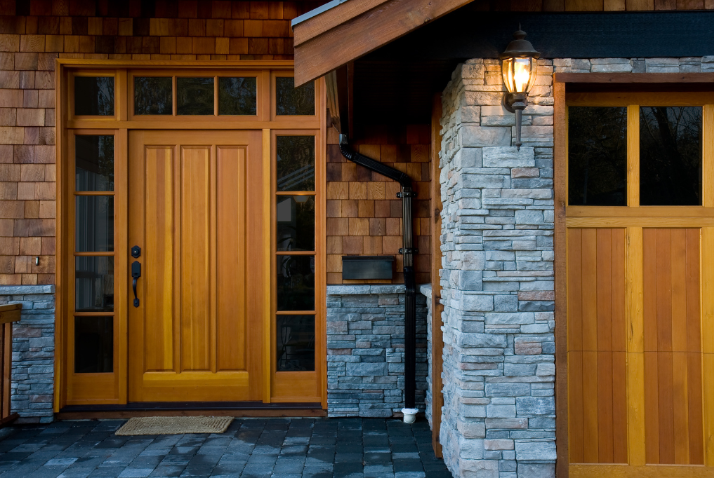 A wooden door with a stained glass window is open to a hallway with stairs.