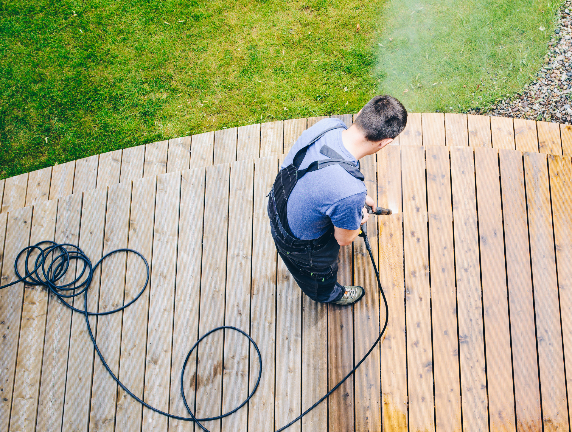 A man is using a high pressure washer to clean a concrete floor.