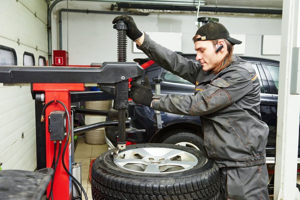 A Man Is Changing A Tire On A Machine In A Garage — SJM Autocare in Mullumbimby, NSW