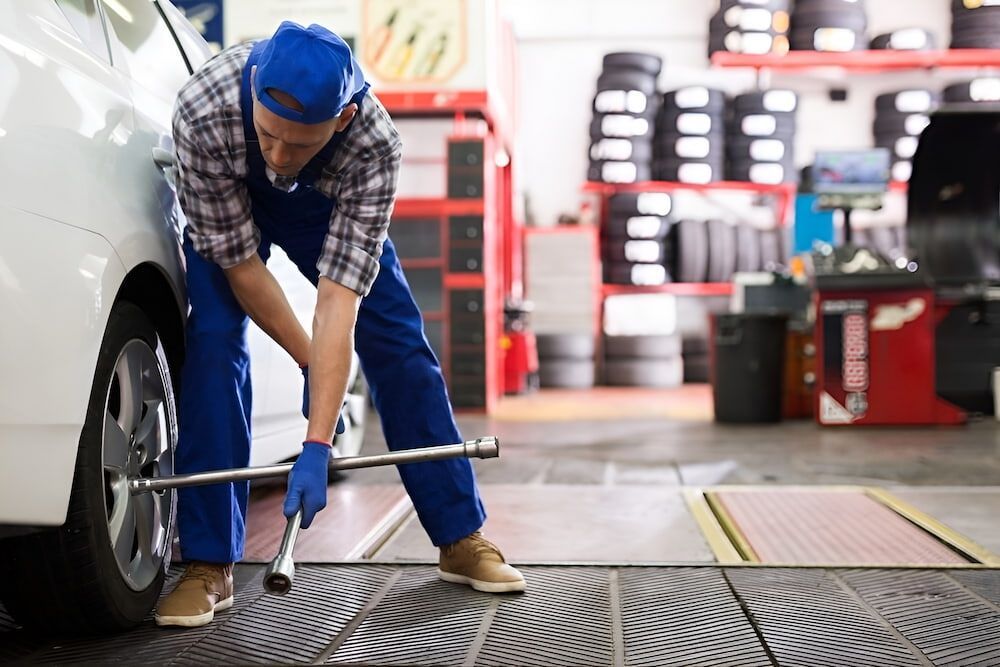 A Man Is Changing A Tire On A Car In A Garage — SJM Autocare in Mullumbimby, NSW