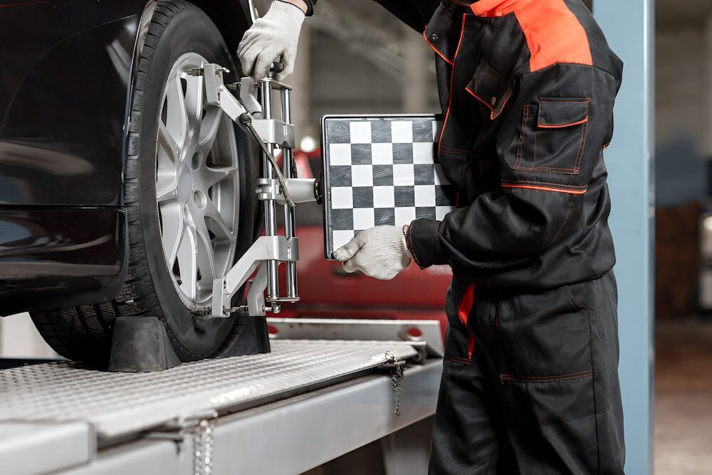 A Man Is Adjusting A Tire On A Car In A Garage — SJM Autocare in Mullumbimby, NSW