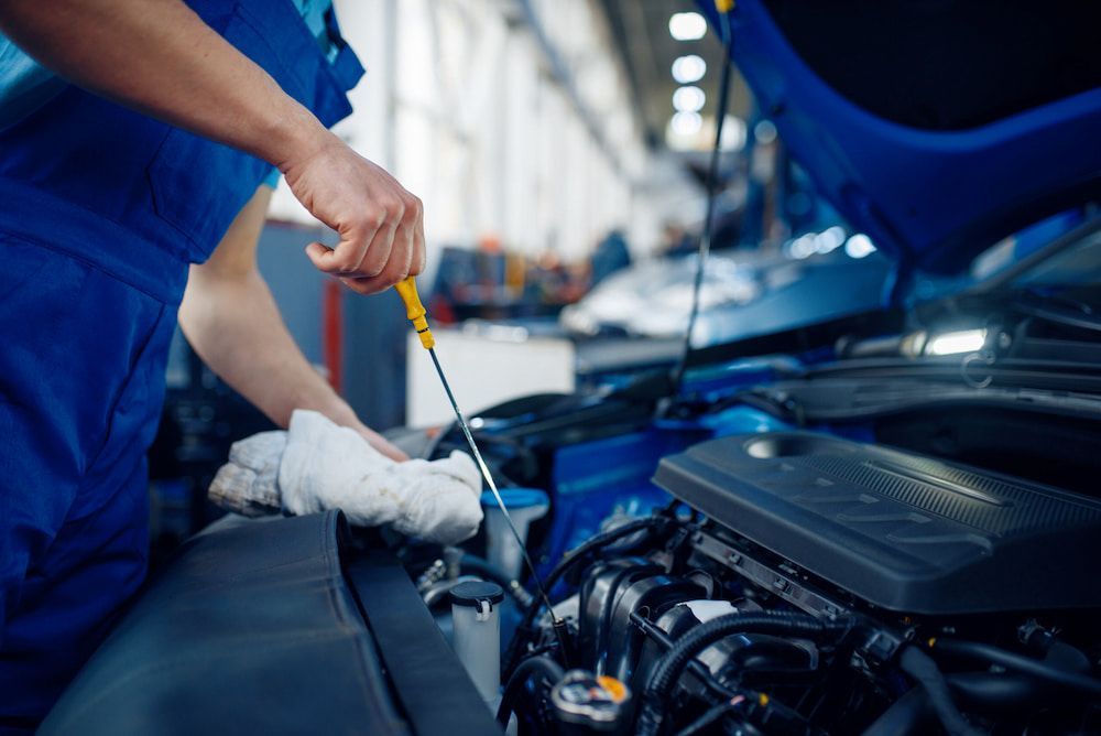 A Mechanic Is Checking The Oil Level Of A Car In A Garage — SJM Autocare in Mullumbimby, NSW