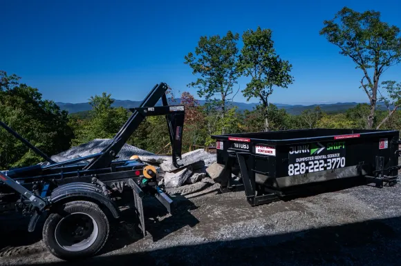 Junk Shift hooklift truck delivering a roll-off dumpster in Western North Carolina