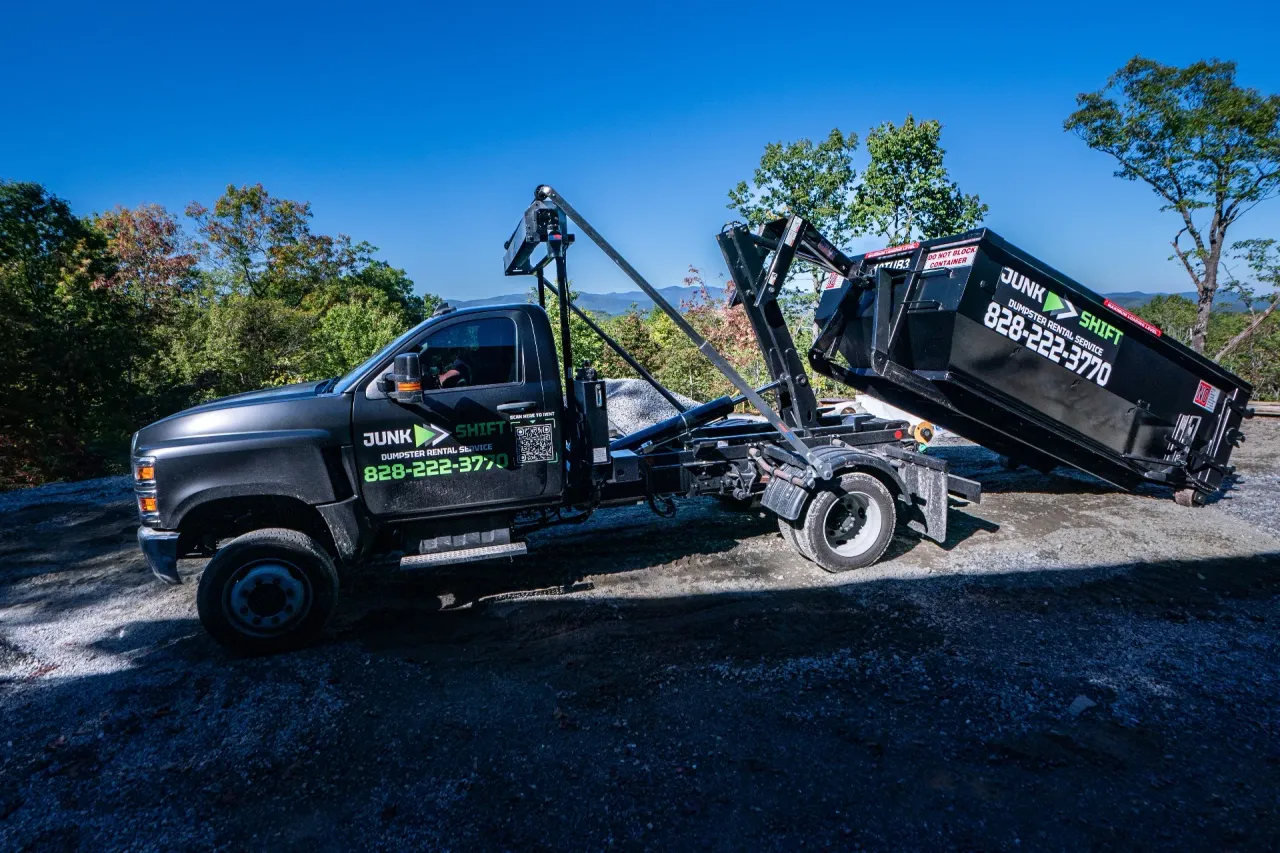 Junk Shift hooklift truck placing a 10 yard roll-off dumpster at a home in Western North Carolina