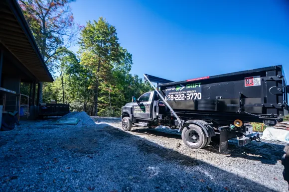 Junk Shift hooklift truck delivering a roll-off dumpster in Western North Carolina