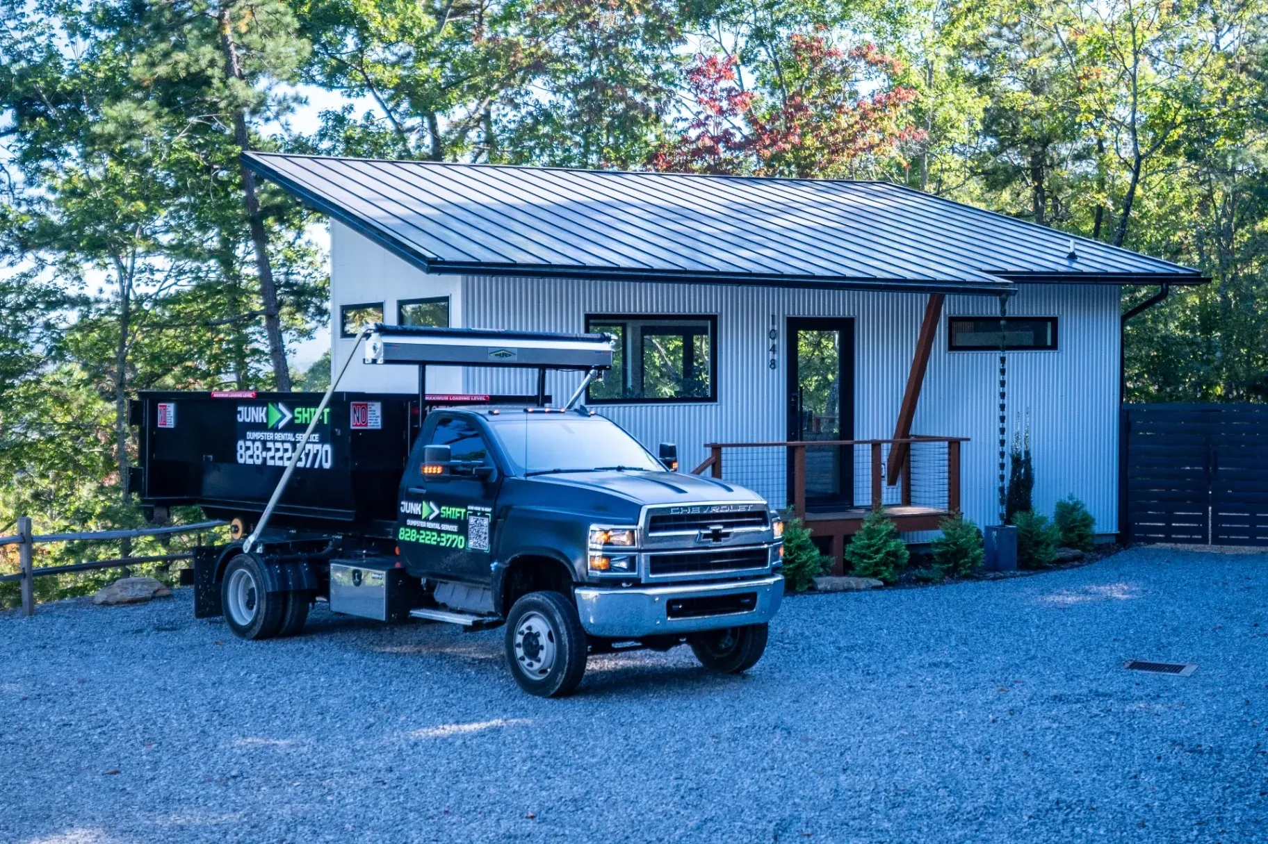 A dumpster is parked in a driveway in front of a house.