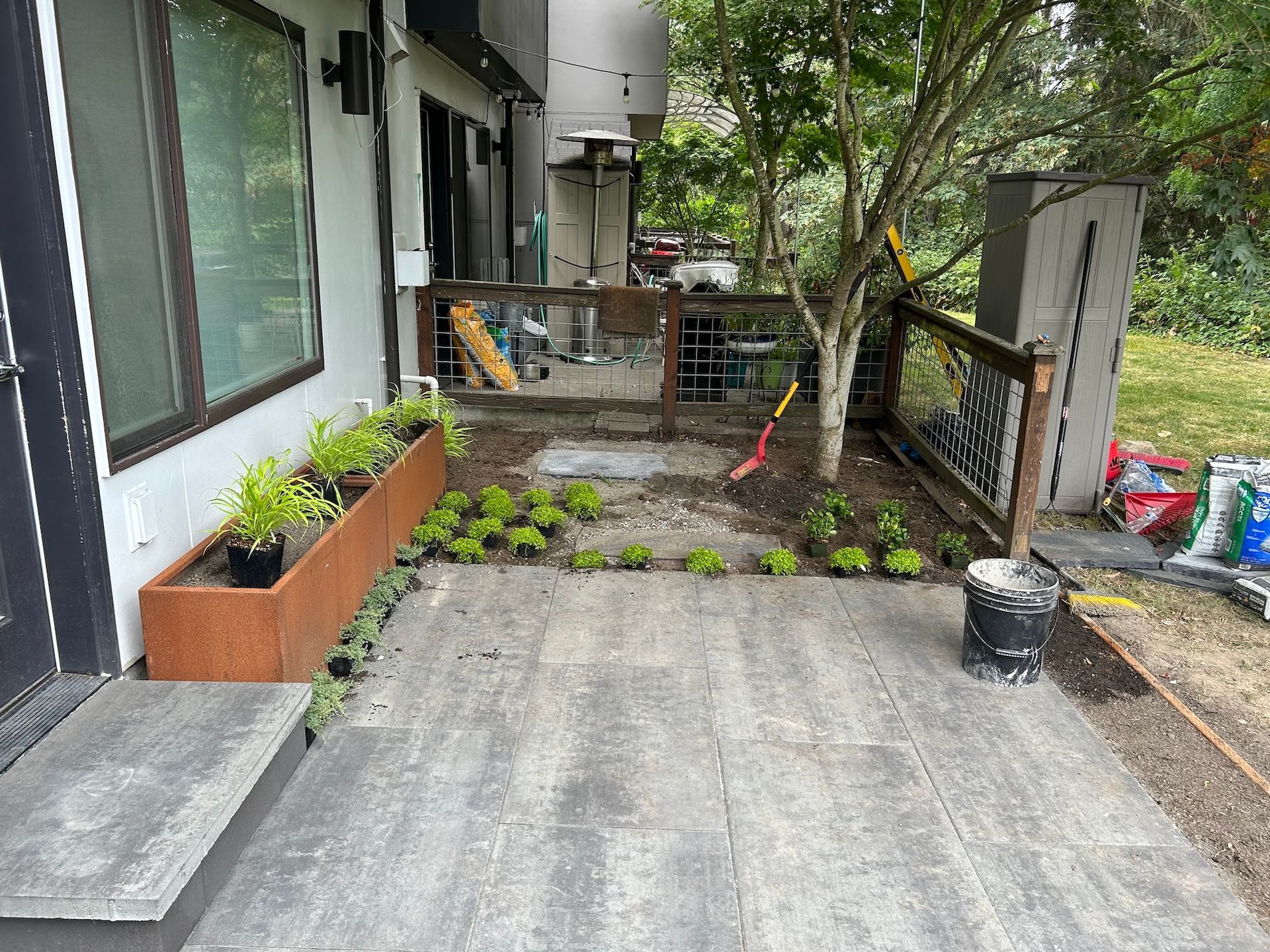 Quiet outdoor patio with concrete floor, potted plants, trees, and railing beside a building