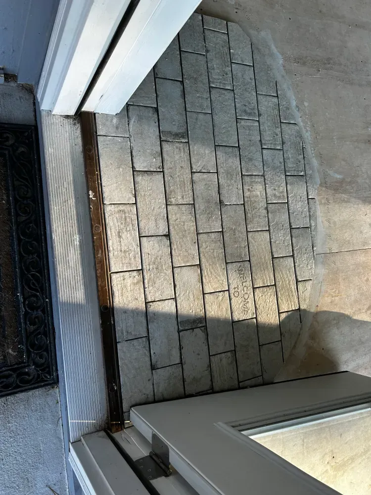 Brick pavers form a semi-circle outside a sliding glass door, next to a white door frame.