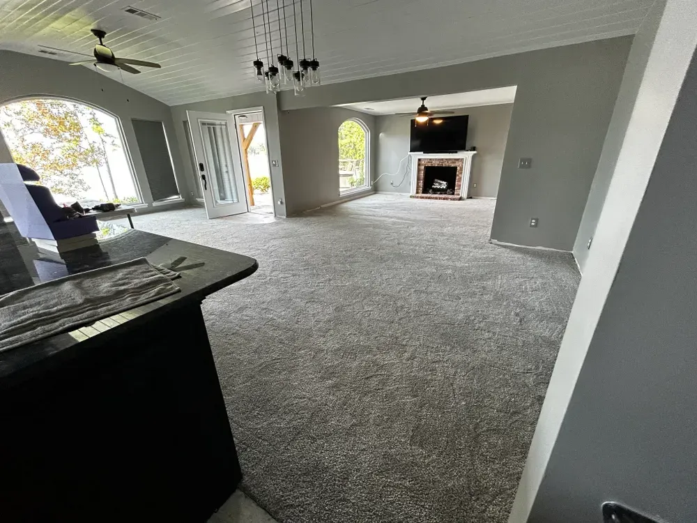 Spacious living room with gray carpet, fireplace, and arched windows. Black kitchen island in foreground.