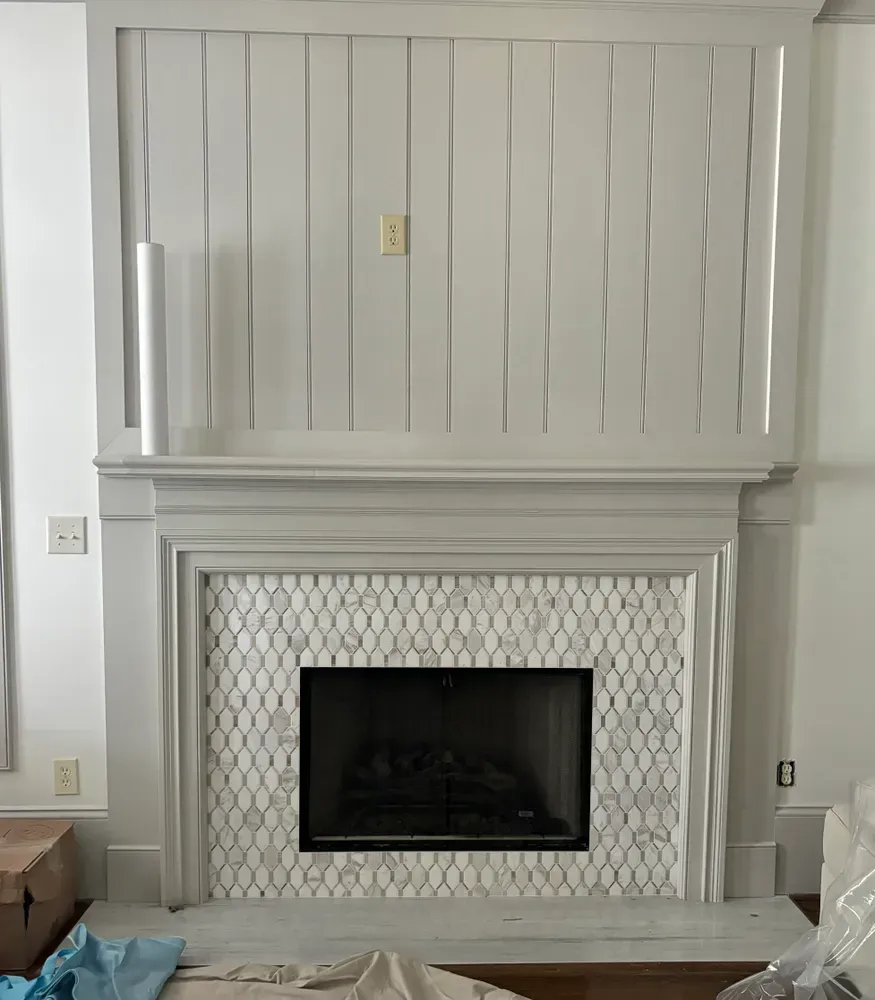 Fireplace with white paneling and a mosaic tile surround.