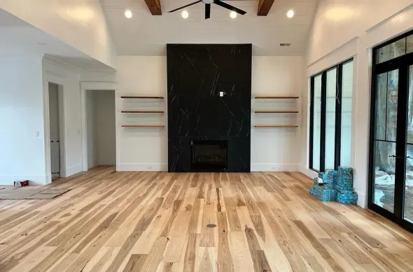Empty living room with wood floors, black fireplace, and built-in shelving.
