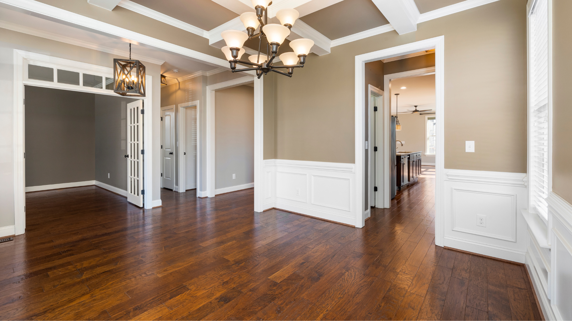 Empty dining room with dark wood floors, white trim, and a chandelier.