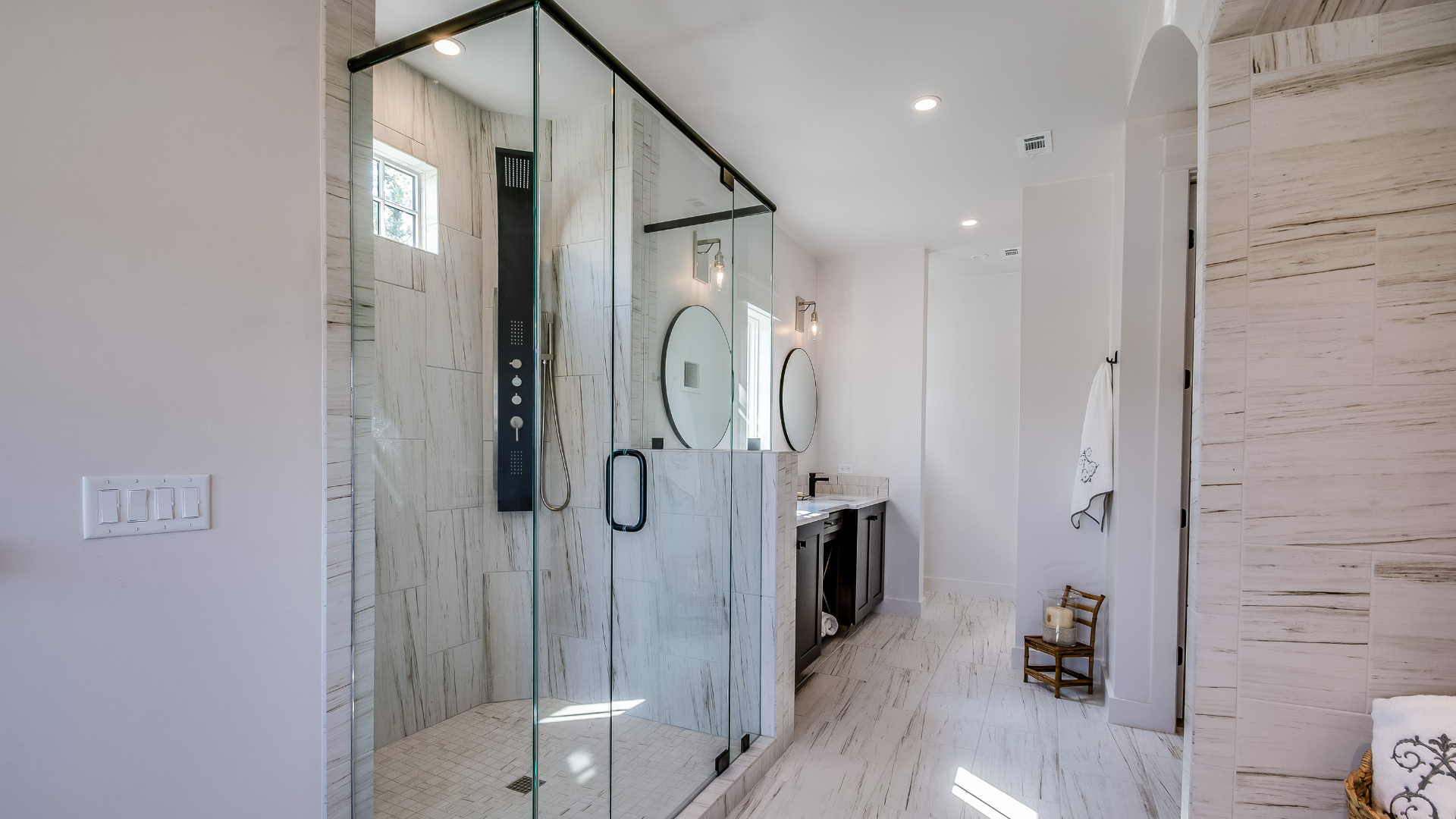Modern white and gray bathroom with a glass shower, vanity, and marble-like walls.