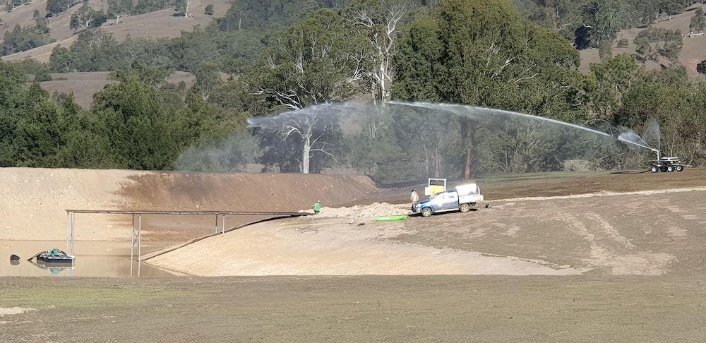 A Sprinkler Is Spraying Water On A Dirt Field — Manning Valley Pumps And Irrigation In Nabiac, NSW