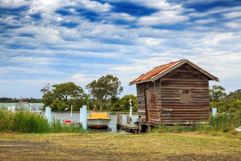 A Small Wooden House Is Sitting Next To A Body Of Water — Manning Valley Pumps And Irrigation In Taree, NSW