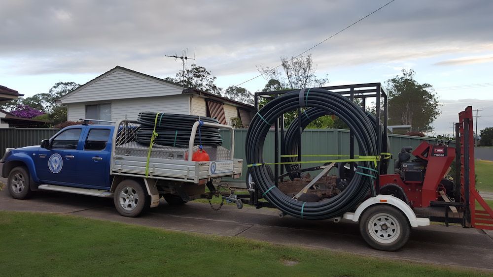 A Blue Truck Is Pulling A Trailer Full Of Pipes — Manning Valley Pumps And Irrigation In Taree, NSW
