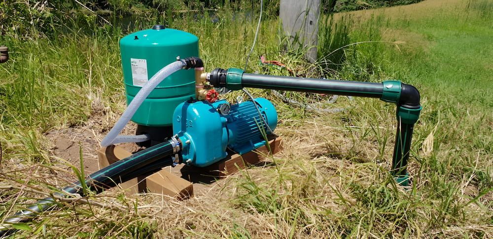 A Water Pump Is Sitting In The Middle Of A Grassy Field — Manning Valley Pumps And Irrigation In Gloucester, NSW