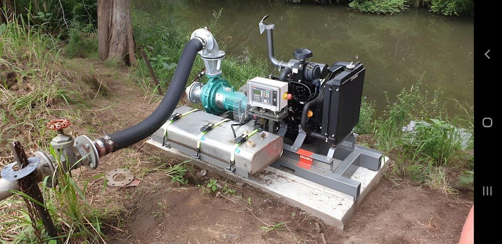A Water Pump Is Sitting On Top Of A Platform Next To A Water — Manning Valley Pumps And Irrigation In Nabiac, NSW