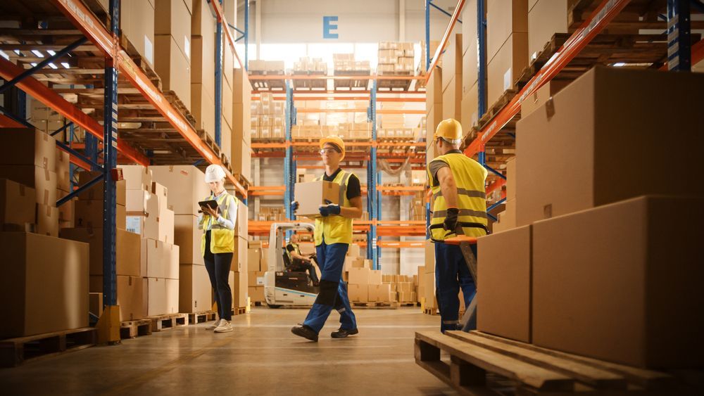 warehouse full of shelves with goods in cardboard boxes, workers scan and sort packages,