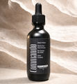 Black dropper bottle labeled “Gommado” on a beige textured background