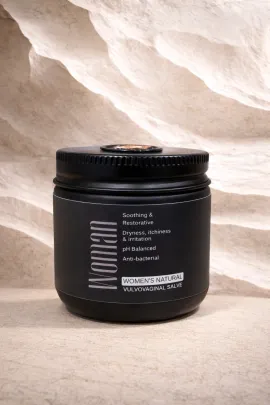 Black jar with white label on a stone surface against a light textured background.