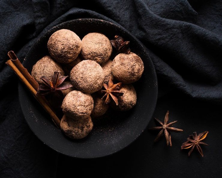 Spoons of golden turmeric and pale coriander seeds with star anise on a dark background