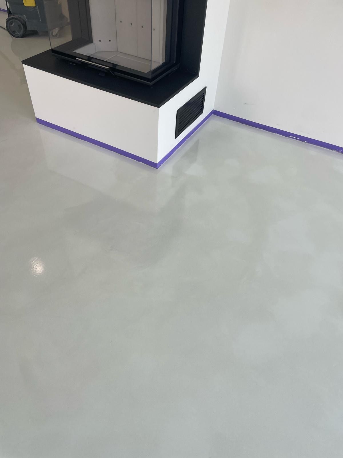Roh showroomu s černobílým kioskem na lesklé šedé podlaze, ohraničený fialovým lemováním