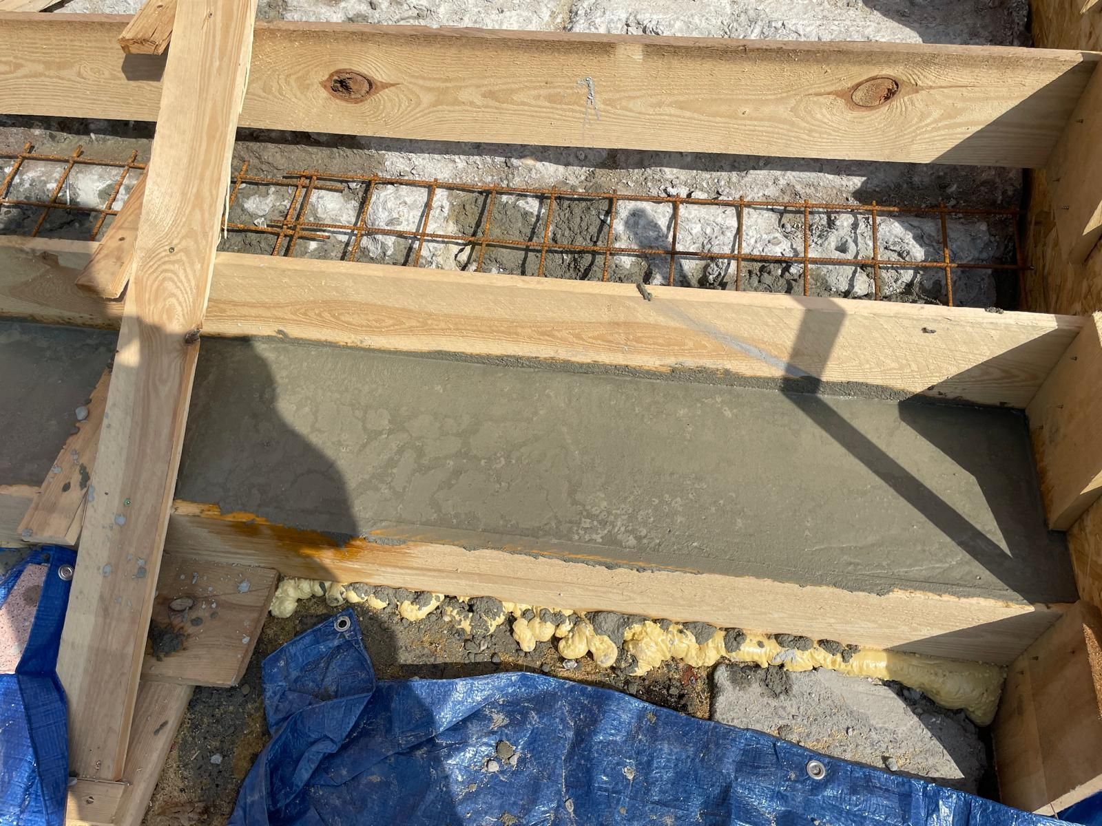 Čerstvý beton nalitý mezi dřevěné bednění a výztuž na staveništi