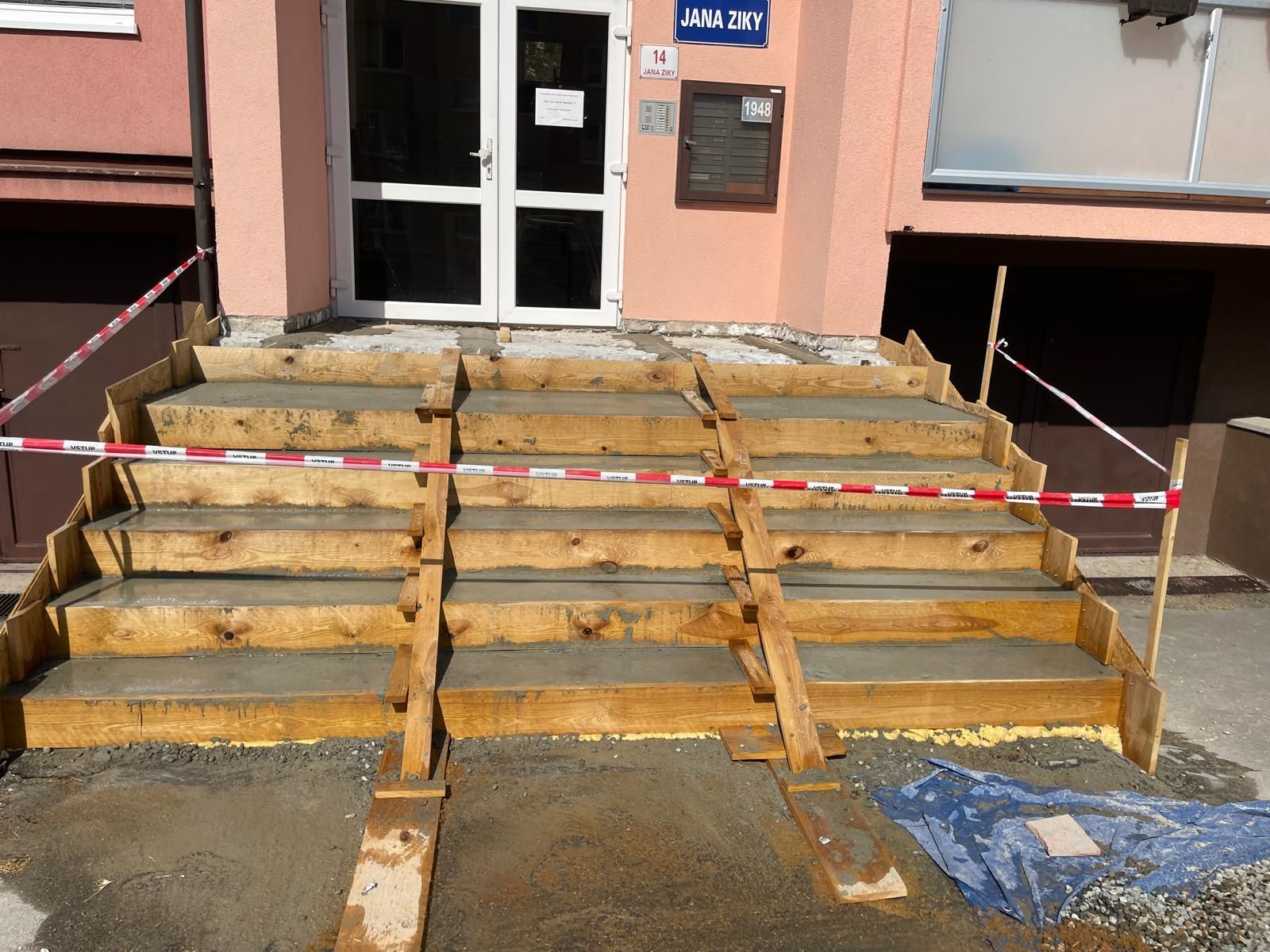 Betonové schody zablokované červenobílou bariérovou páskou před vchodem do budovy