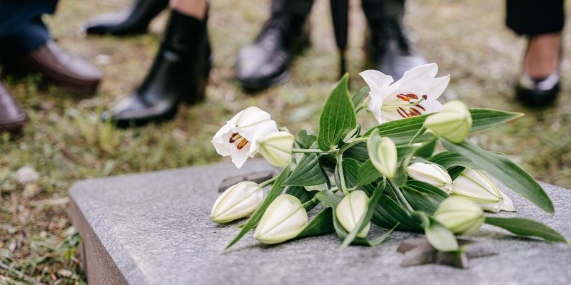 White lilies placed on a gravestone during a memorial service, honoring a loved one with support from a funeral home and cremations in Kennesaw, GA.