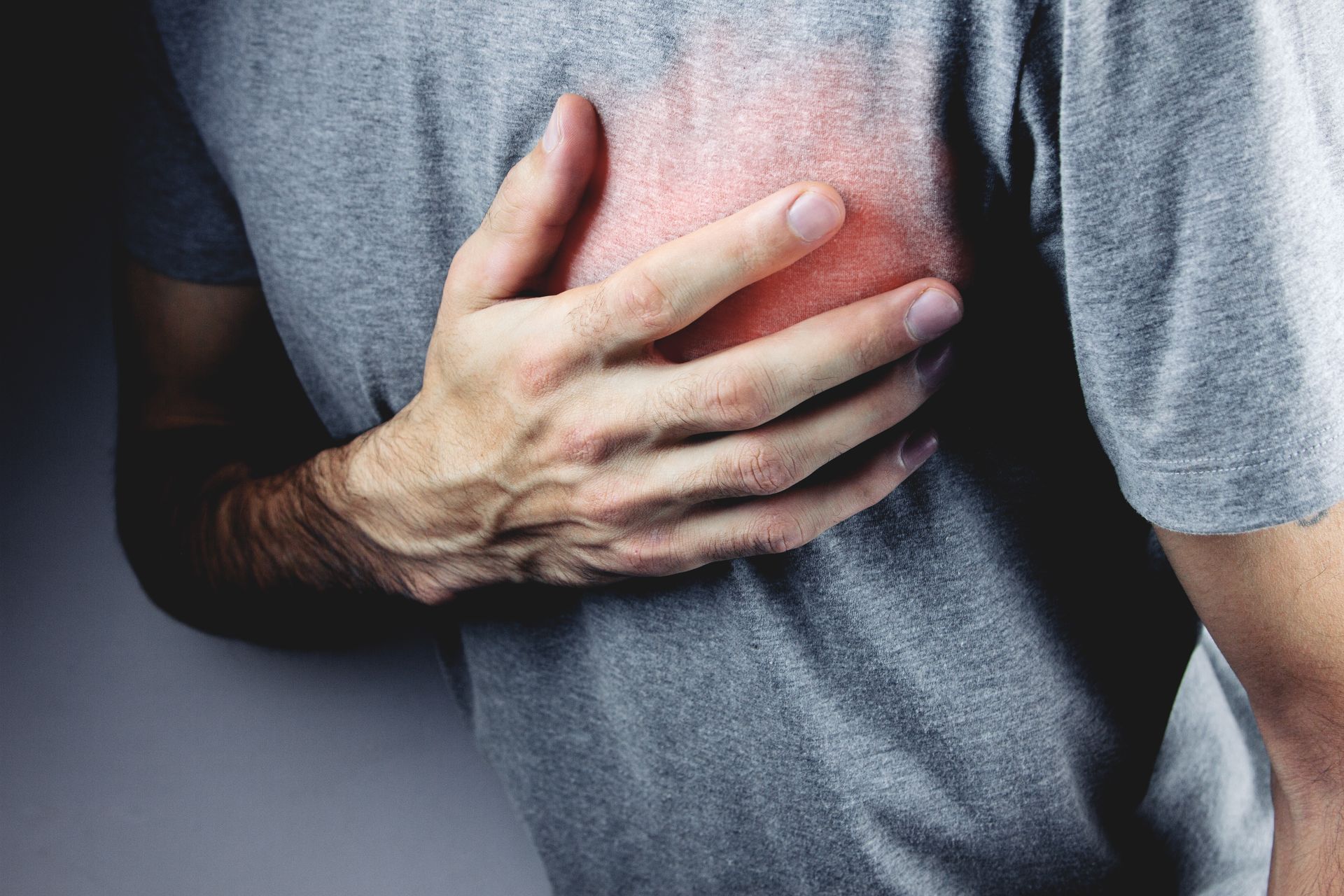 A man is holding his chest in pain because he has a heart attack.