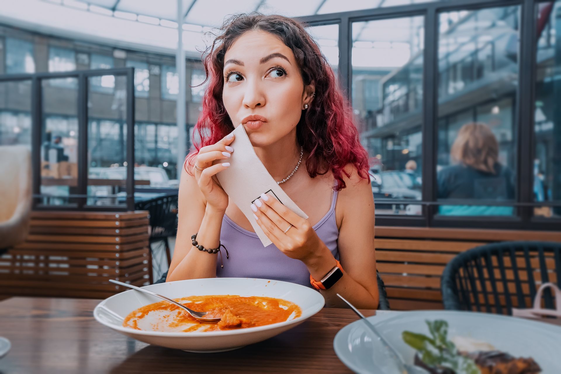 A woman is sitting at a table with a bowl of soup and a receipt.