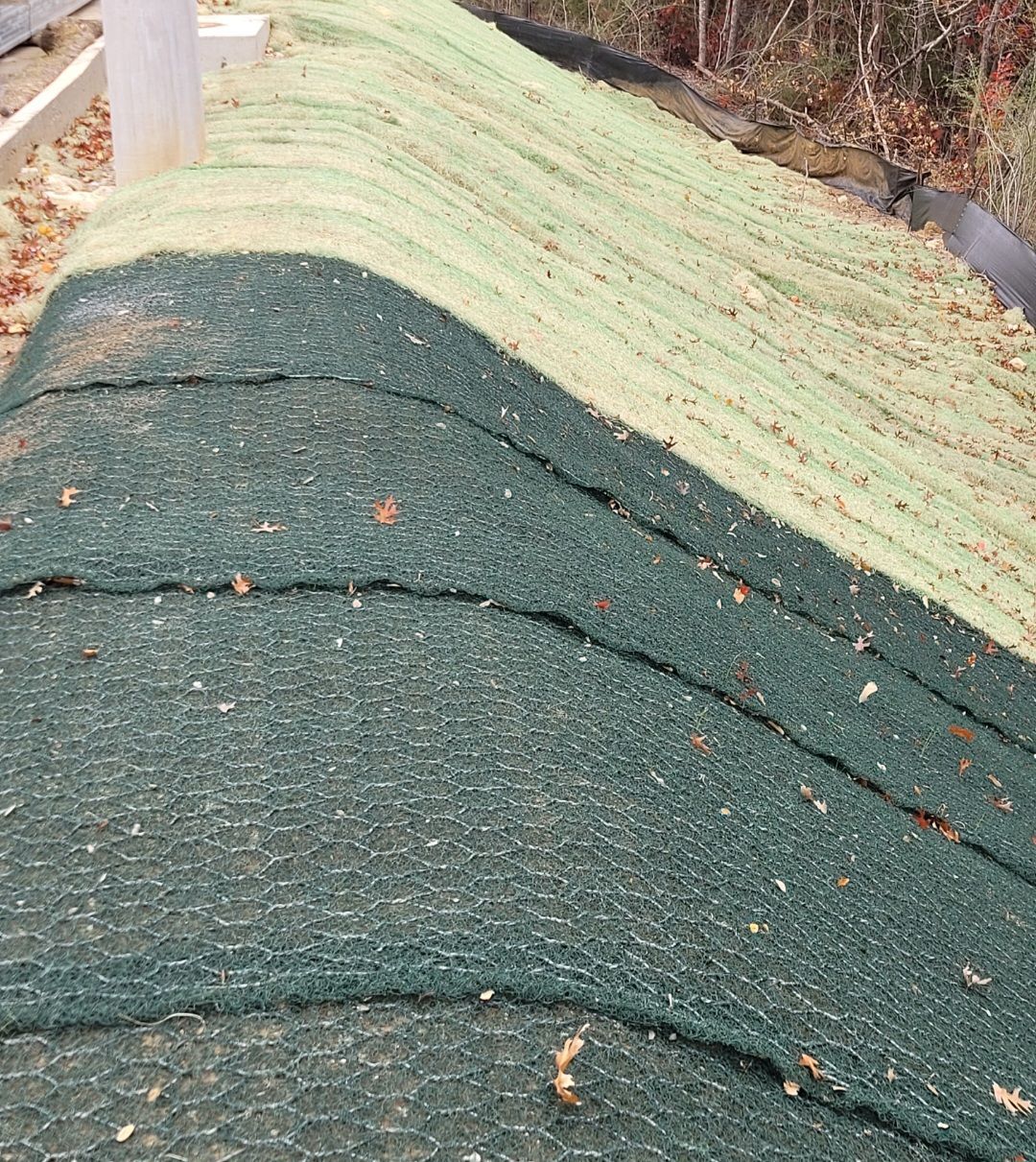 Green roof underlayment being installed on a sloped roof, with seams and scattered debris visible