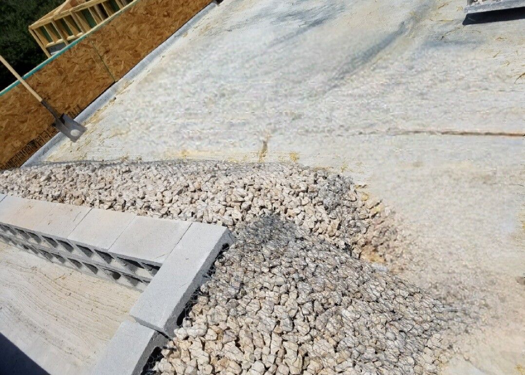 Cracked concrete driveway with a gravel patch and cinder blocks along the edge