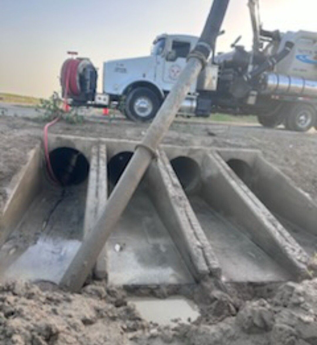 Storm drain culvert with muddy runoff and a utility truck above the concrete embankment
