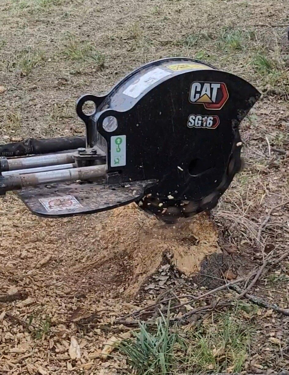 CAT SE16 excavator attachment on the ground beside a patch of disturbed dirt and grass