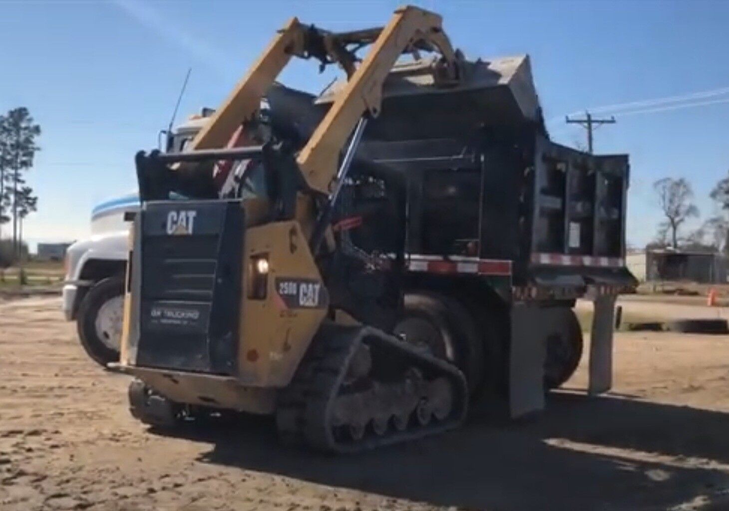 CAT skid steer loading dirt into a dump truck at a construction site