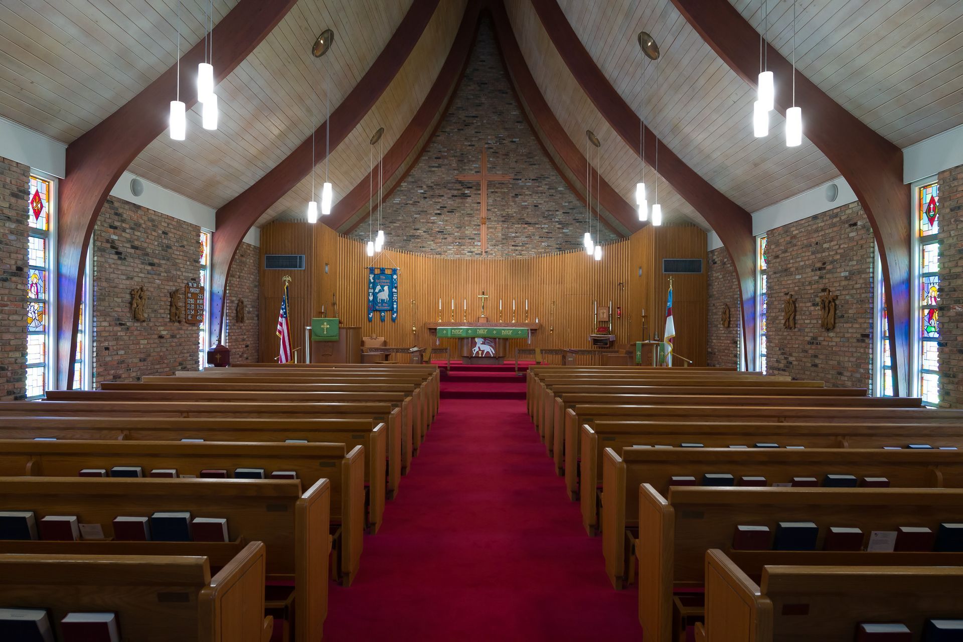 The inside of a church with wooden benches and a red carpet