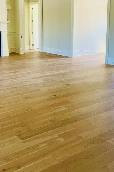 Empty room with light wood floors and white walls, viewed from a doorway.