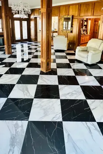 Elegant room with black-and-white checkered marble floor, wood paneling, chandelier, and white chairs