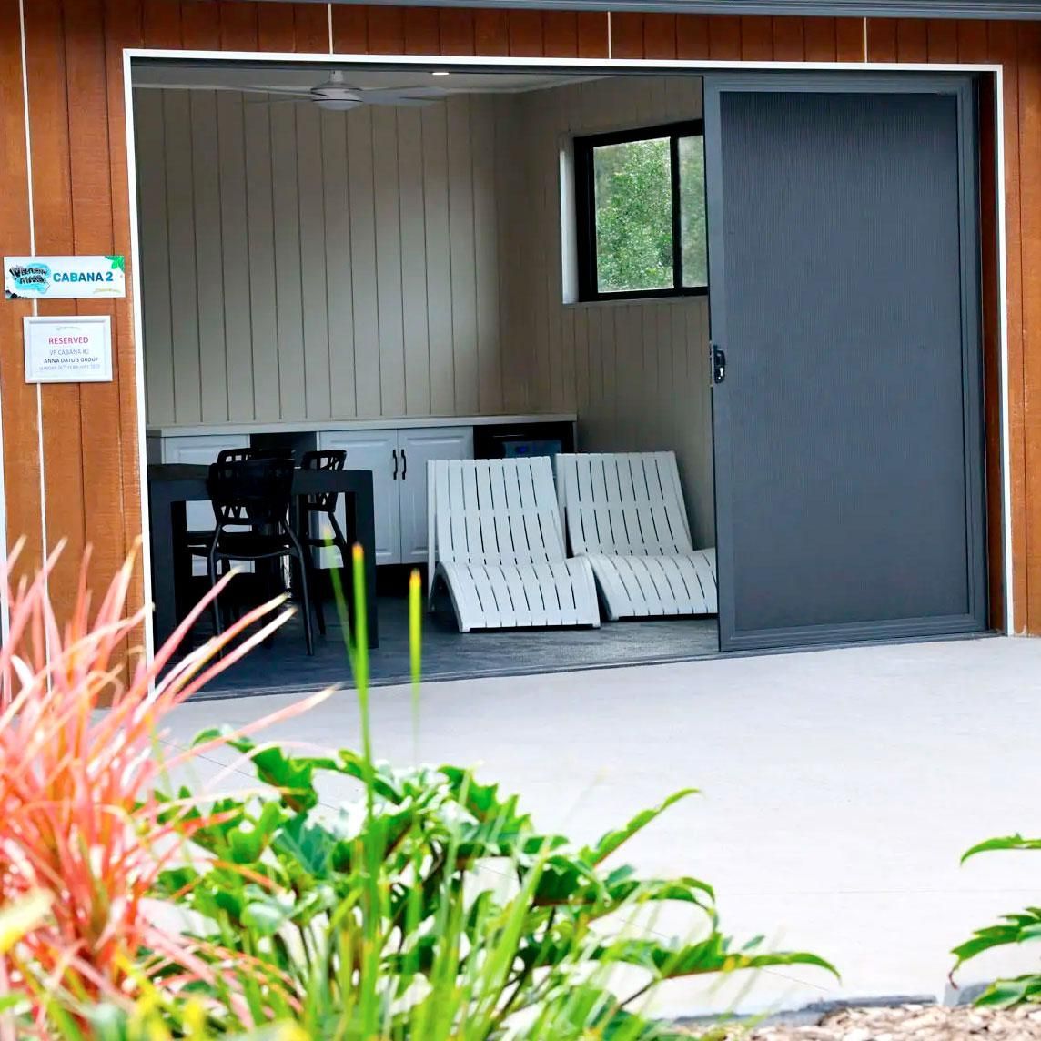A Sliding Garage Door Is Open to A Room with Chairs and A Table — Creative Commercial Furniture in Byron Bay, QLD