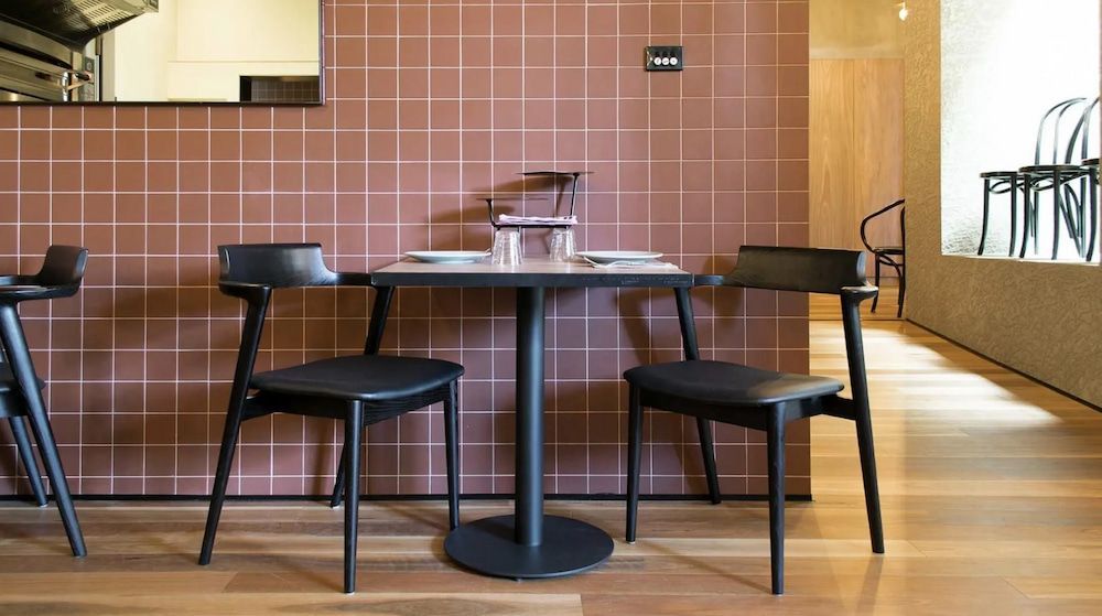 A Restaurant with A Table and Chairs in Front of A Red Tiled Wall — Creative Commercial Furniture in Cairns City, QLD