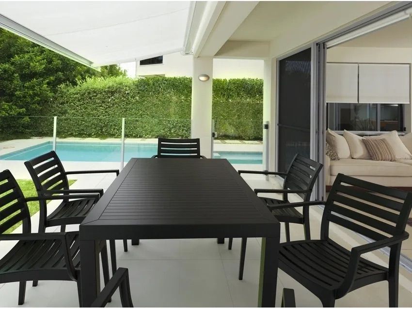 A Table and Chairs on a Patio With a Swimming Pool in the Background — Creative Commercial Furniture in Cairns City, QLD 