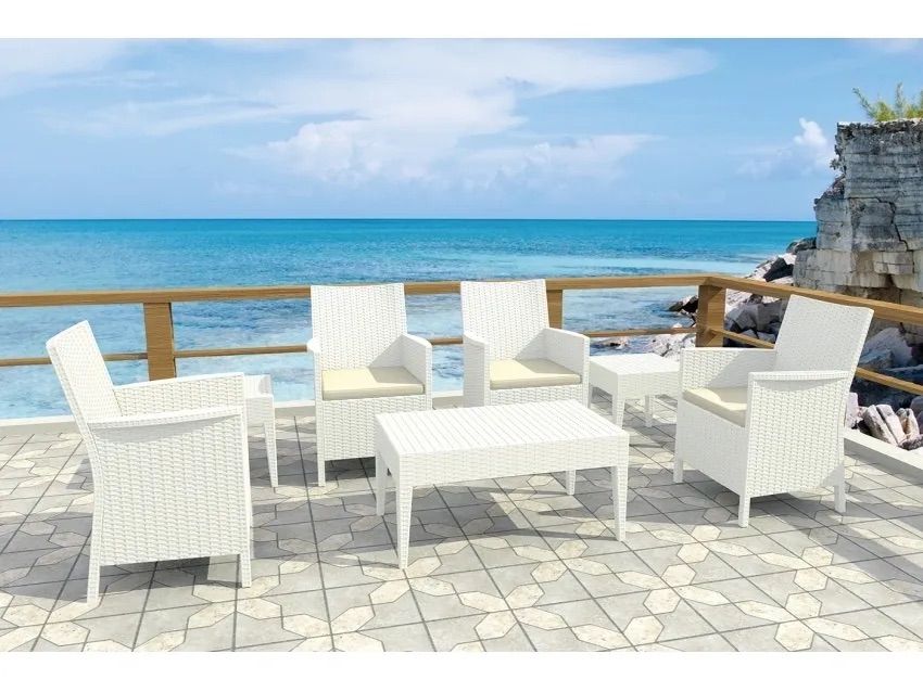 A White Wicker Patio Set is Sitting on a Tiled Deck Overlooking the Ocean — Creative Commercial Furniture in Cairns City, QLD 