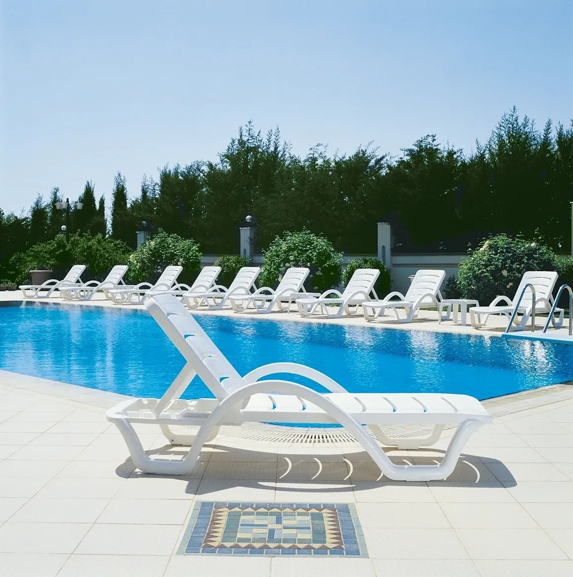 A Row of White Lounge Chairs Next to a Swimming Pool — Creative Commercial Furniture in Cairns City, QLD 