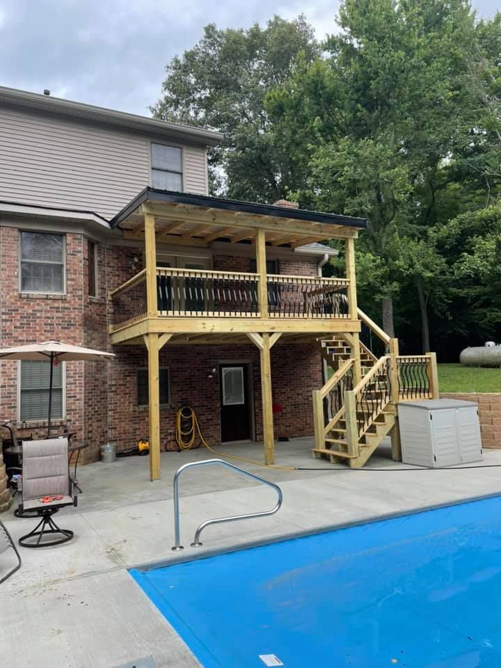 Backyard deck with stairs and railings beside a brick house, next to a swimming pool