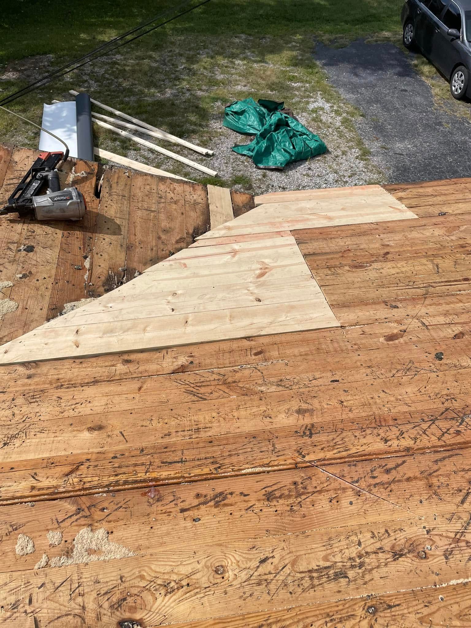 Wooden ramp under construction beside a gravel path, with tools and boards on the ground.